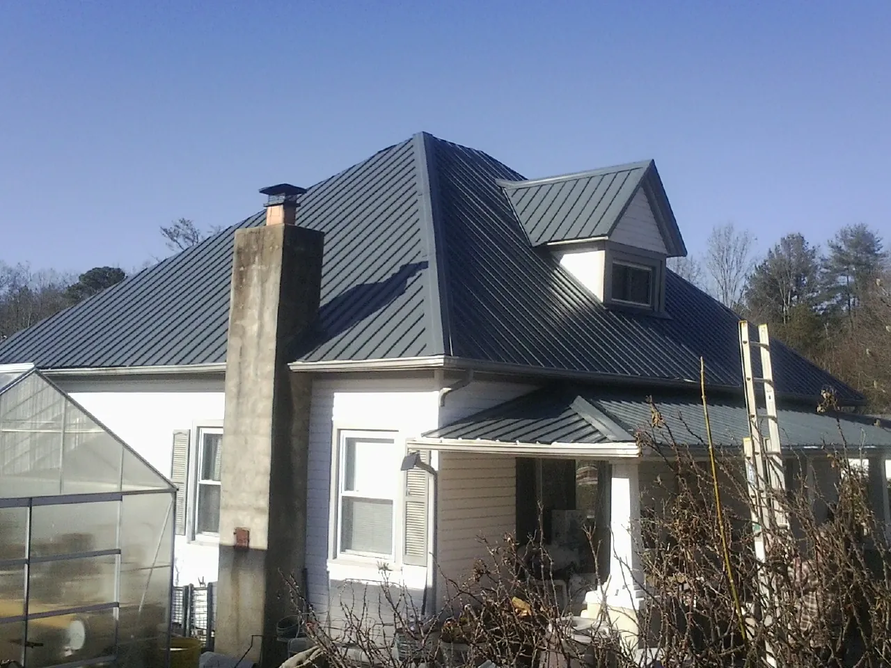 Dark blue standing seam metal roof on a white farmhouse with dormer — Slate & Tile Roof Repair by Roofing Brothers in North Salem