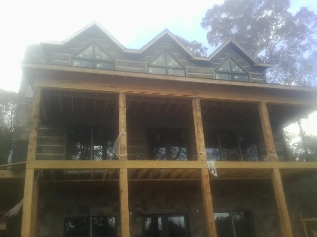 Dormers and porch framing on a large log home under construction — Roof Coating work by our crew in North Salem