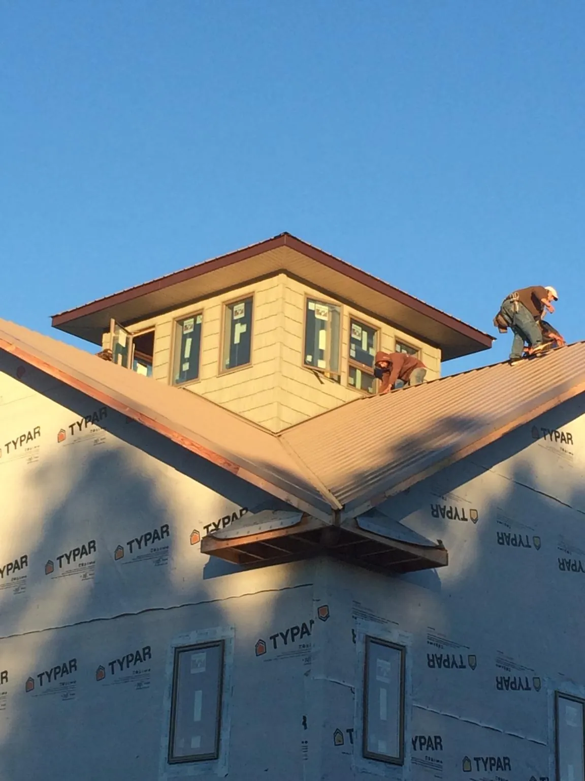 Roofers working around a rooftop cupola on a new metal roof at sunset — Roof Waterproofing in North Salem by Roofing Brothers